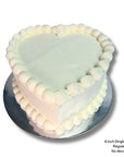 White love heart birthday cake with simple white piping and icing