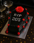 Cake designed like a tombstone with 'RIP 20's' text and red roses on a black background