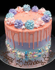 A round birthday cake with a pastel gradient from peach to lavender, decorated with piped frosting rosettes, sprinkles, and a drip design. It sits on a silver cake board with 'Happy Birthday Eve' written in chocolate script against a black background.