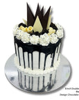 Black drip cake and white icing with chocolate shards on a white background
