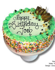 Birthday sponge cake with green icing, sprinkles, and 'Happy Birthday Josh' text on a white background.