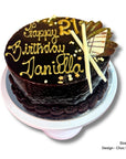 Chocolate birthday cake with gold decorations on a white background
