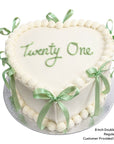 White double height love heart cake with green ribbons and birthday message