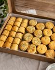Box of assorted small pies on a wooden table with a plant in the background