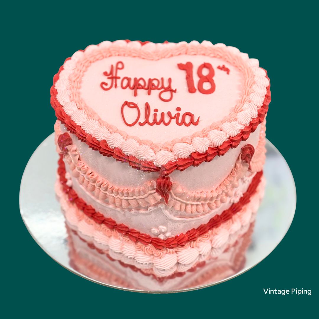Pink and red birthday cake with 'Happy 18 Olivia' heart shaped cake with retro piping