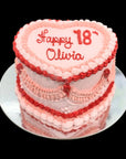 Pink and red birthday cake with 'Happy 18 Olivia' heart shaped cake with retro piping