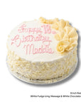 A round red velvet cake with cream cheese filling and white chocolate scroll decorations with pink birthday message.