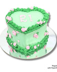 Heart-shaped cake with green and pink decorations on a white background
