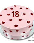 Round sponge cake with pink icing and red piped love hearts for birthday celebration