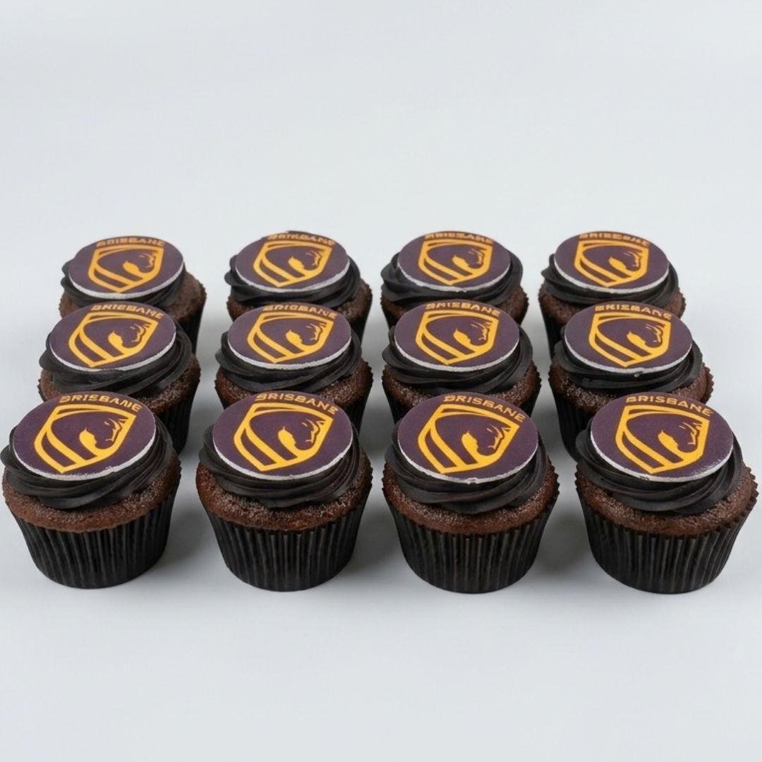Twelve chocolate cupcakes arranged in two rows on a light gray background, each topped with dark chocolate frosting and a circular topper featuring a gold and purple Brisbane Broncos logo.