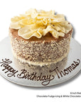 Red velvet birthday cake with chocolate icing and white chocolate sides and scrolls on top. Message written in chocolate 'happy birthday thomas'