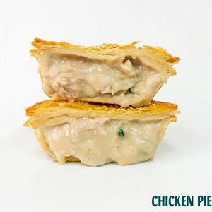 Two halves of a golden-brown flaky pie crust filled with a creamy chicken and mushroom mixture, stacked on a white background with 'CHICKEN PIE' text in the bottom right corner.