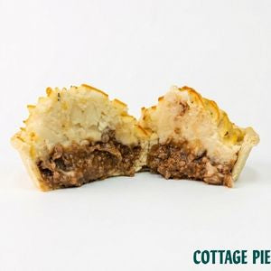 A cut open cottage pie showing a golden-brown pastry crust, a creamy white topping, and a brown meat filling, set against a plain white background with 'COTTAGE PIE' text in the bottom right corner.