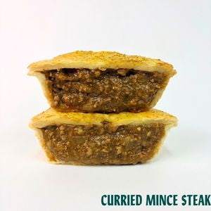 Two halves of a cut pie or mince steak with a thick, textured brown curry filling and golden-brown crust, stacked on a white background with the text 'CURRIED MINCE STEAK' at the bottom.