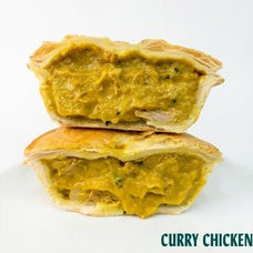 Two halves of a curry chicken pie stacked on top of each other, showing a thick yellow-orange curry filling with visible green herbs, on a white background with the text 'CURRY CHICKEN' in the bottom right corner.