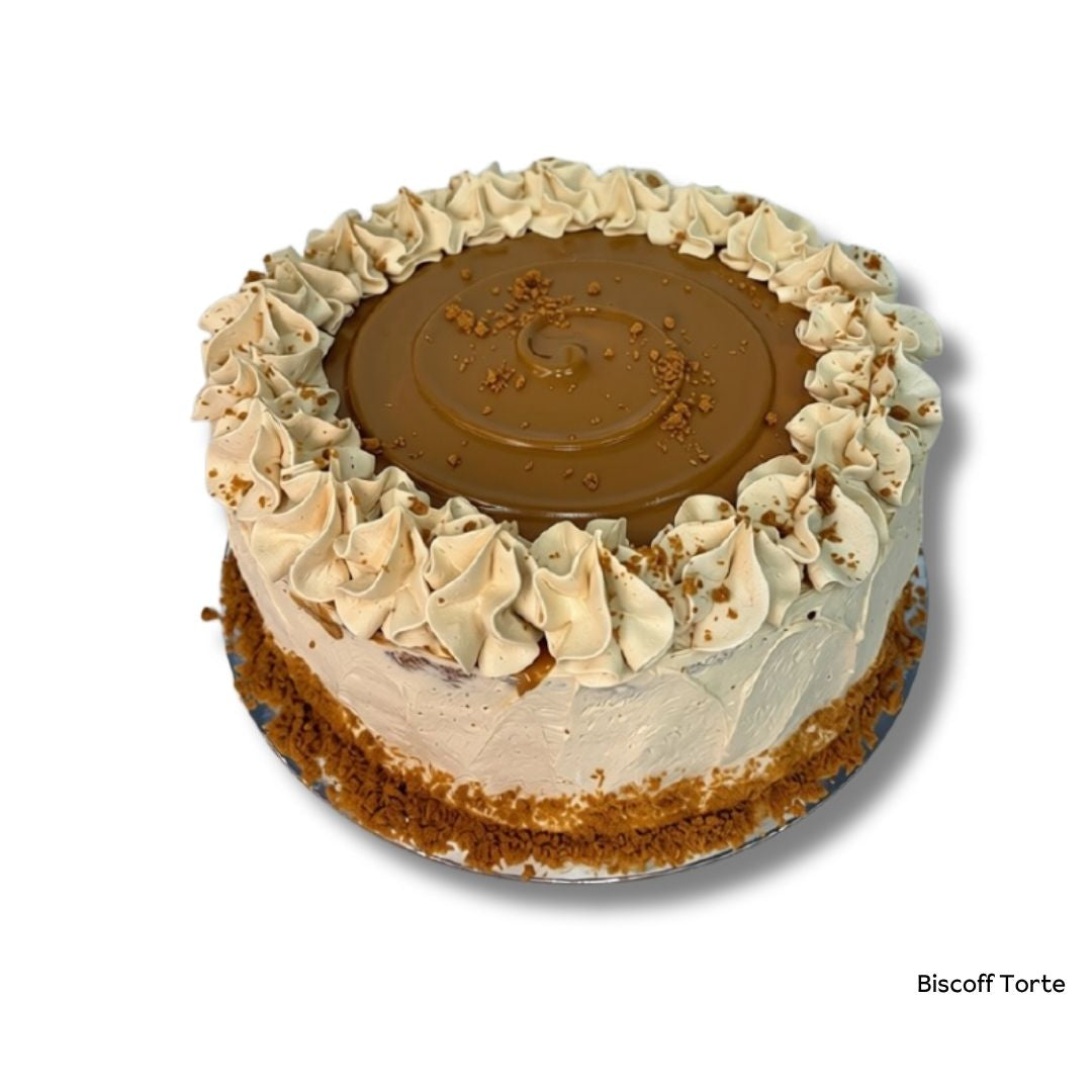 A round Biscuit Torte cake with a glossy brown caramel-like center, piped cream frosting, and cookie crumbs, shown on a white background with the text 'Biscoff Torte' in the bottom right corner.
