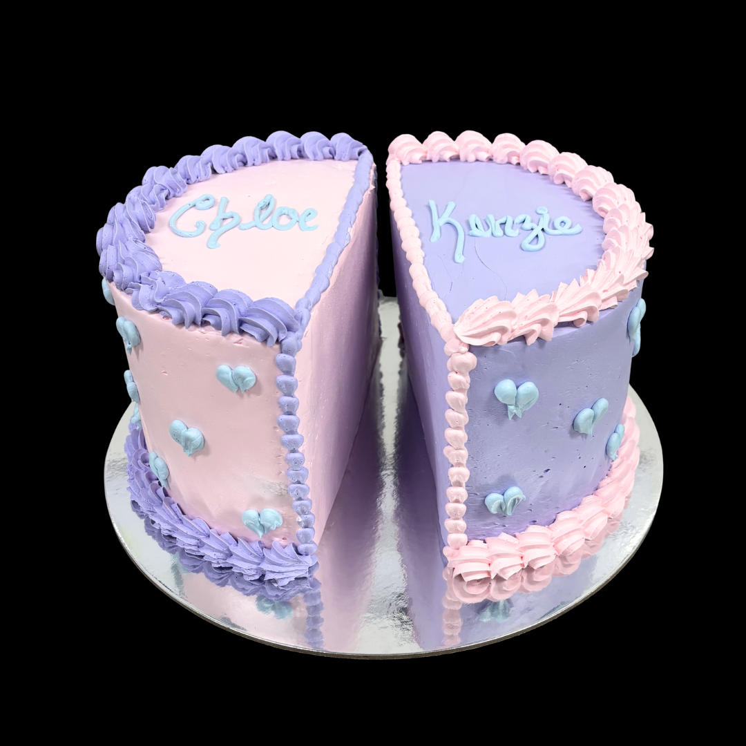 Two-tiered cake with two name written on top, one side pink and one side purple