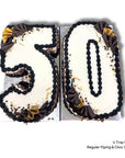 A birthday cake shaped into the number 50 with chocolate piping and gold and chocolate wedges