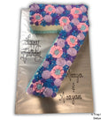 Floral cake shaped like the number 7 with 'Happy Birthday' and names on a white background