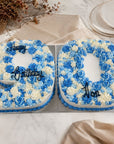 Two floral birthday cakes shaped like the number '90' on a marble surface.