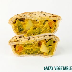 Two halves of a satay vegetable pie stacked vertically on a white background, showing a filling of mixed vegetables and a golden-brown pastry crust with black sesame seeds. The text 'SATAY VEGETABLE' is visible in the bottom right corner.