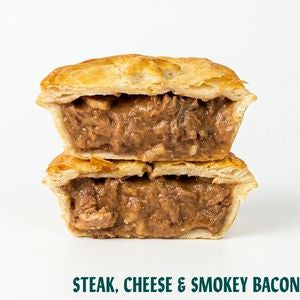 Two stacked halves of a baked steak pie with a golden flaky crust and a savory meat filling, shown on a white background with the text 'STEAK, CHEESE & SMOKEY BACON' at the bottom.