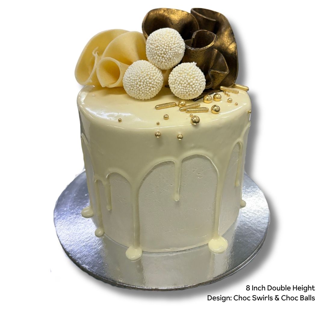 White drip cake with chocolate swirls and balls on a silver cake stand
